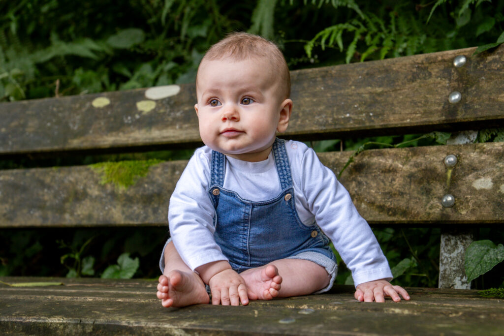 Kindershooting outdoor - Baby auf Bank im Wald