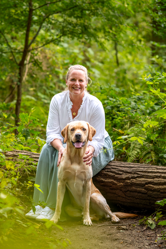Hundeshooting outdoor - Frau mit ihrem Hund im Wald auf Baumstamm sitzend