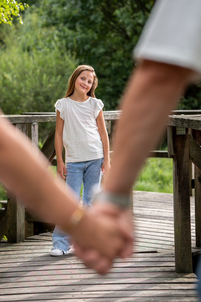 Familienshooting draußen - Hände der Eltern unscharf im Vordergrund, dazwischen Kind